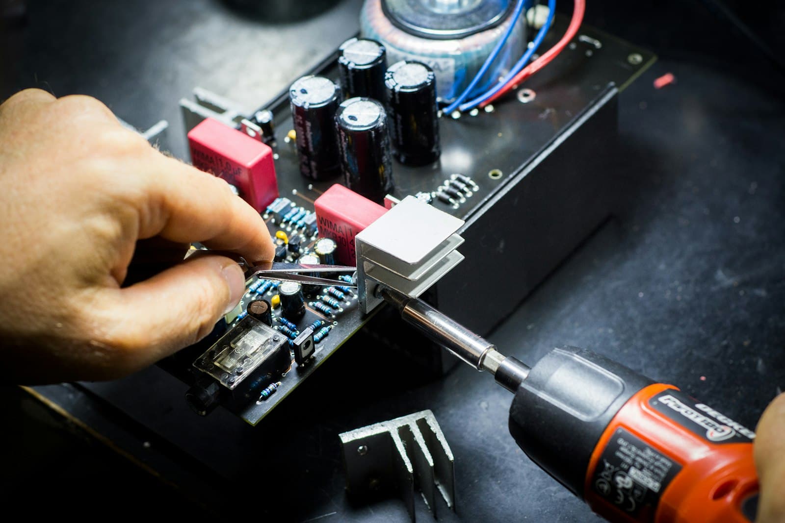 Hands fitting a component onto a circuit board at a workbench